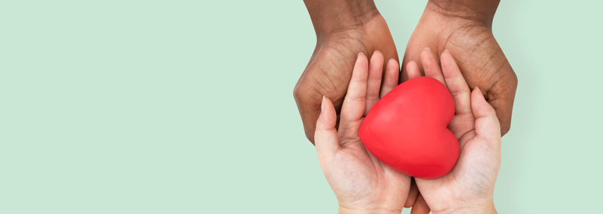 imagem com duas mãos segurando um coração vermelho para doação de sangue